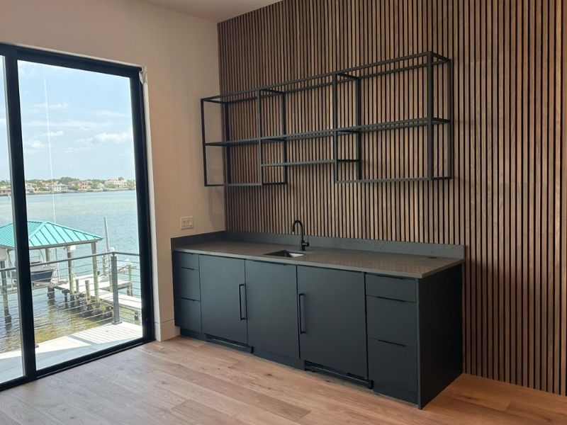 BLACK CABINETS WITH A PATIO VIEW Black cabinets with a sink with and a brown wall