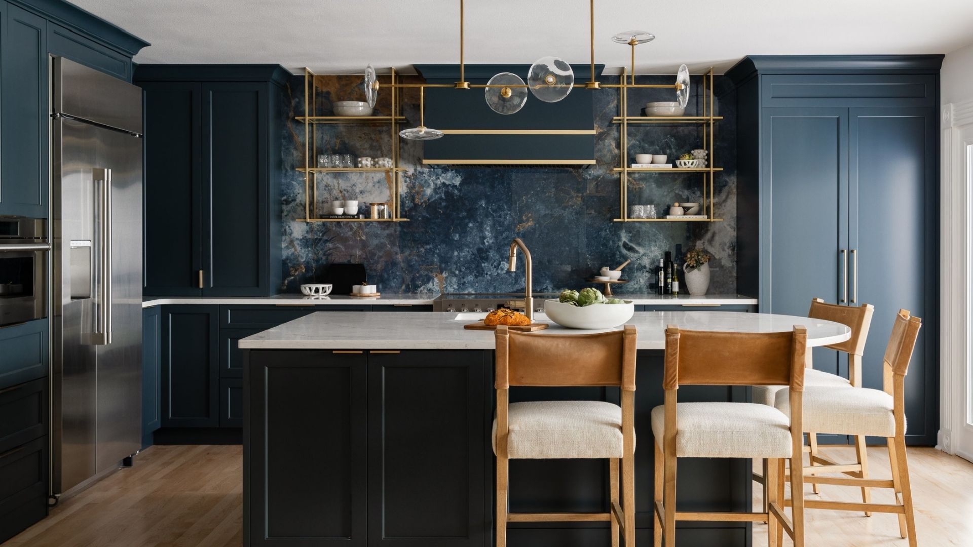 Modern Kitchen with Navy Blue Cabinets and Large Island Modern kitchen with navy blue lower cabinets, white upper cabinets, a large island with white countertop and built-in sink, complemented by pendant lights and stainless steel appliances.
