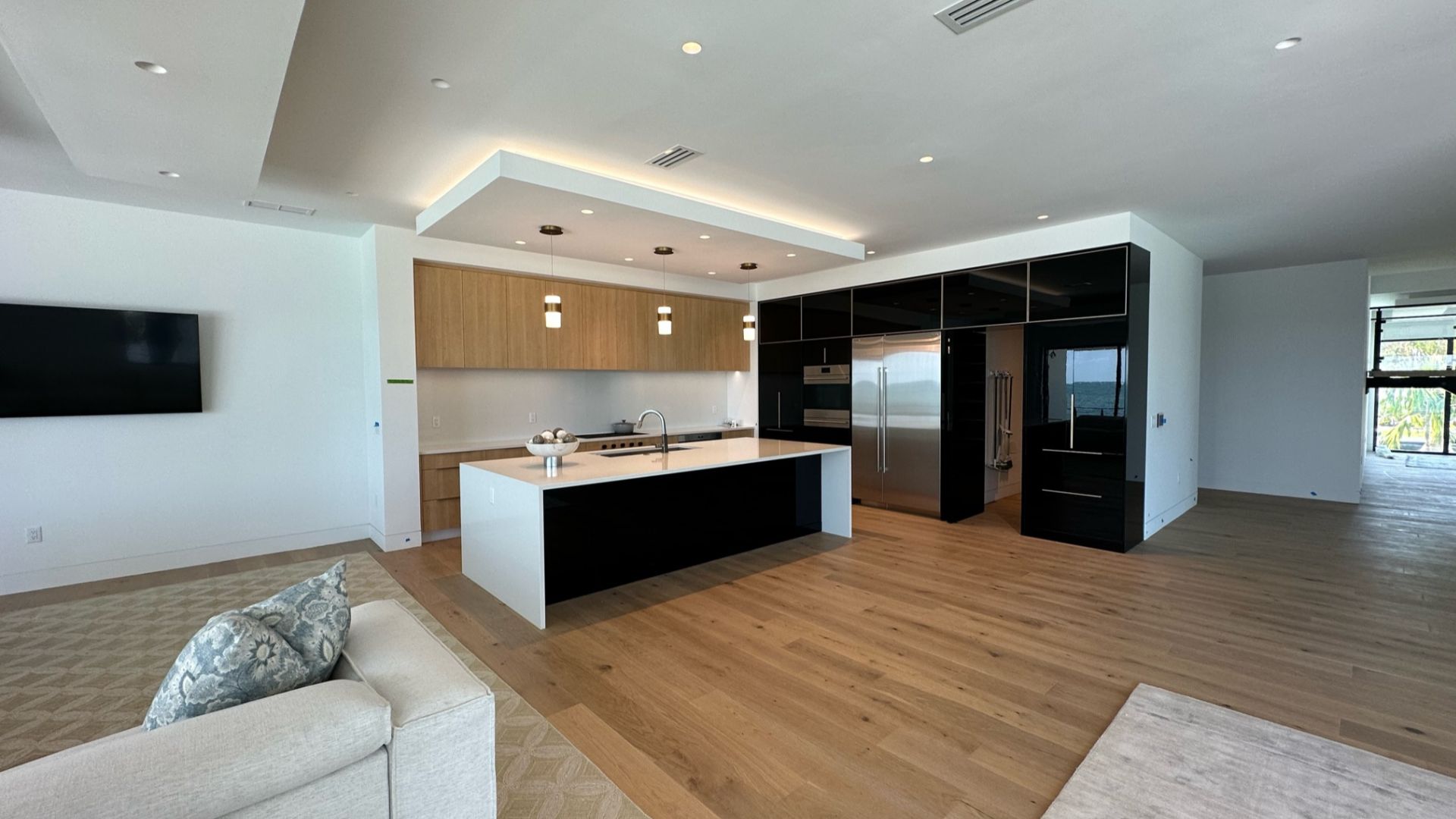 Modern Kitchen with brown upper cabinets and black cabinets on the side with an island