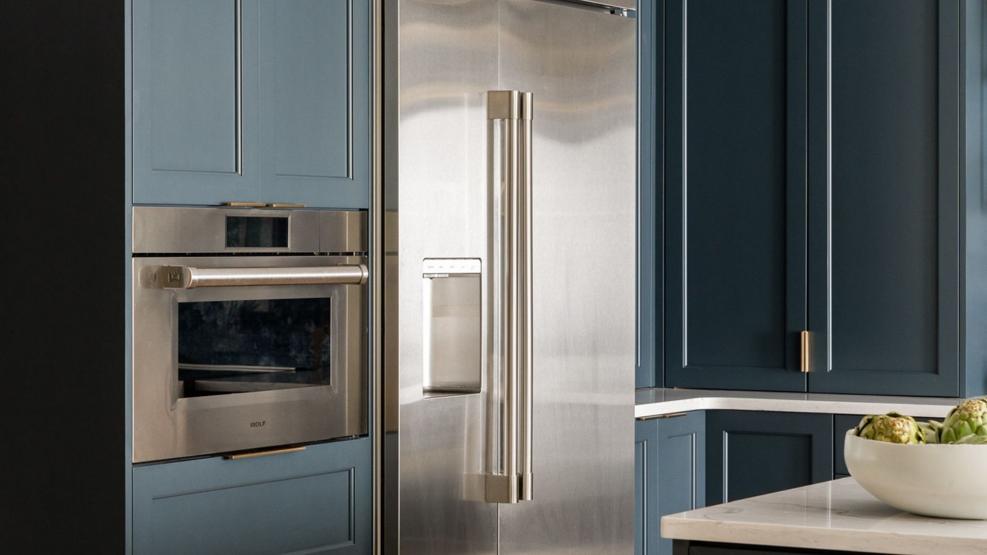 Elegant Blue Kitchen with Gold Hardware and Marble Backsplash White Kitchen Cabinetry with gold handlers and mini fridge
